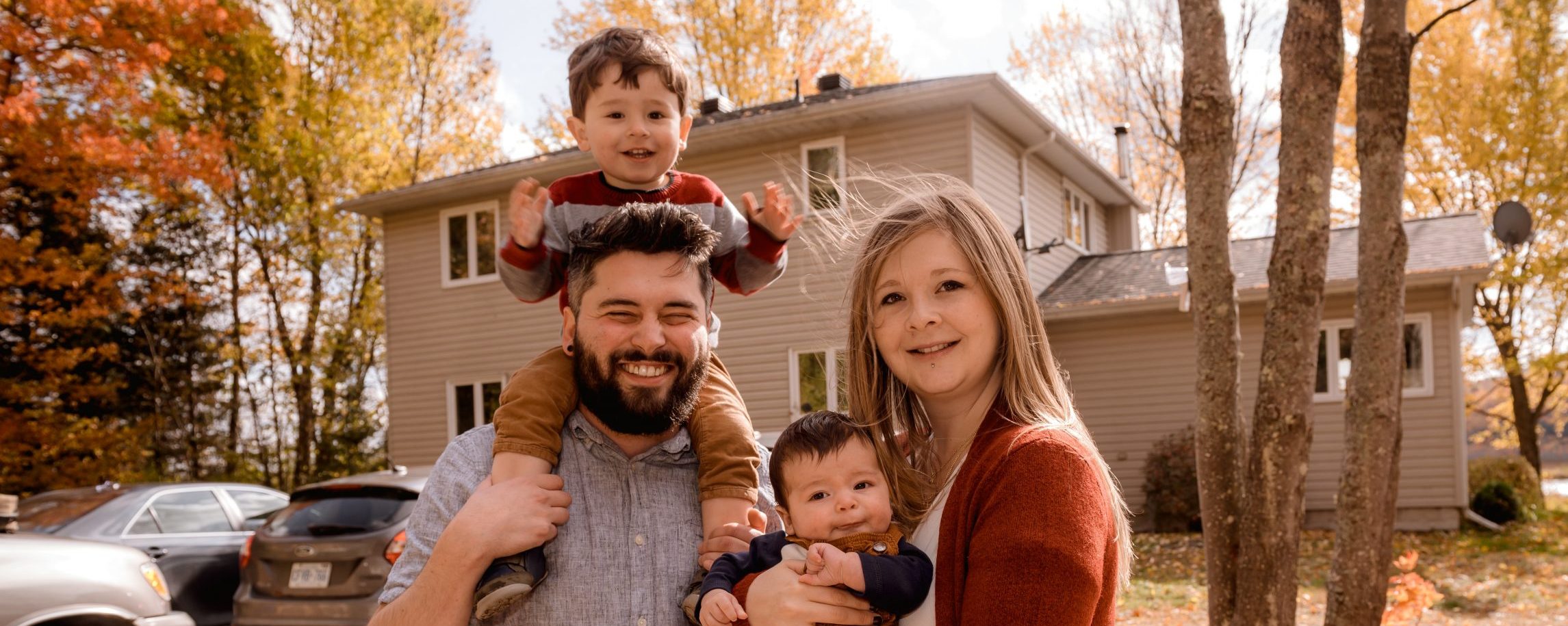 Family smiling outside the home they bought with help from Century 21 Realty Services